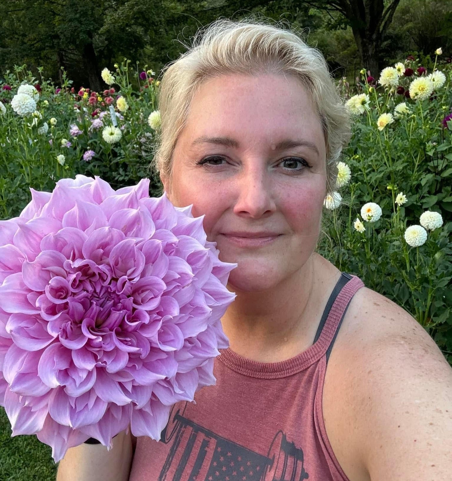 Summer meadow dahlia farm owner posing with large pink dahlia in Waverly, Iowa